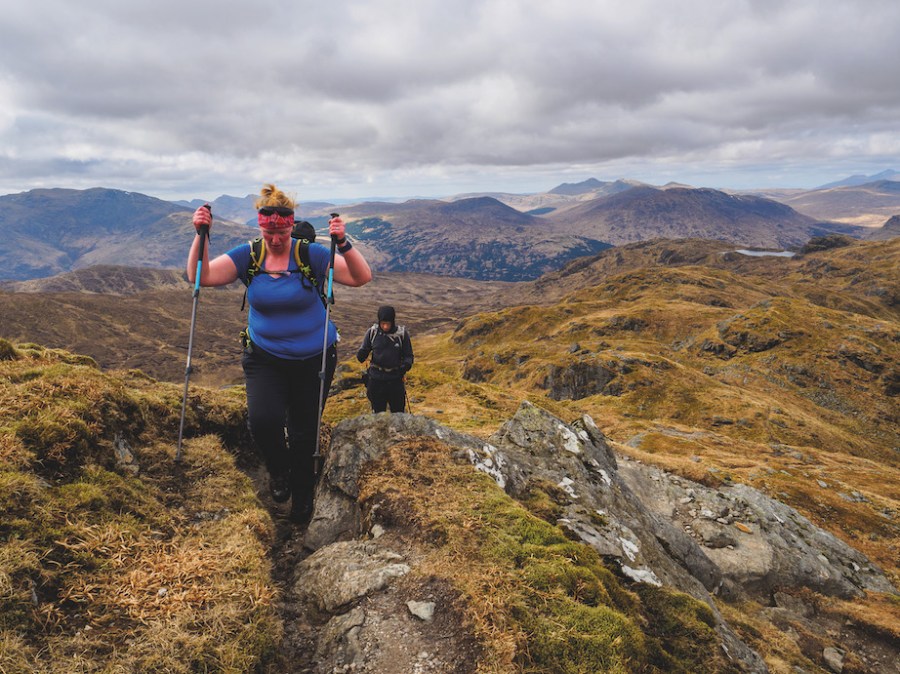 Woman in a black and white jacket looking down at the ground in Glen Coe