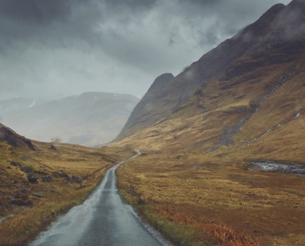 Concrete single track road through brown glassland in bad weather, Glen Etive, Argyll