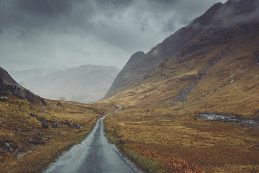 Concrete single track road through brown glassland in bad weather, Glen Etive, Argyll