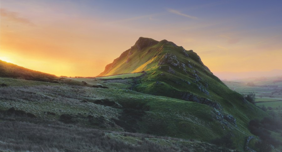 Misty, muticoloured sunrise sky behind Chrome Hill, Peak District