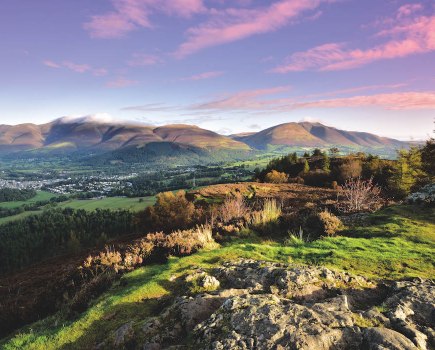 Purple sky with pink clouds over a panoramic view of a valley