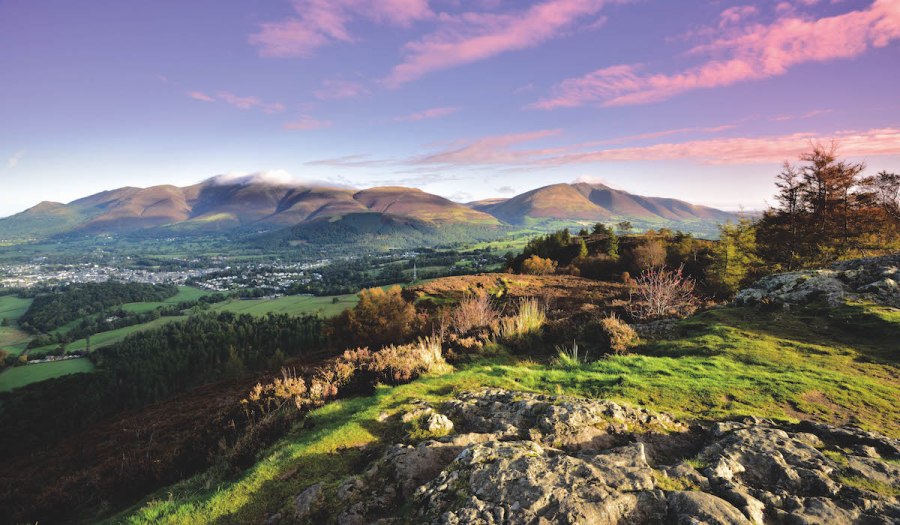 Purple sky with pink clouds over a panoramic view of a valley