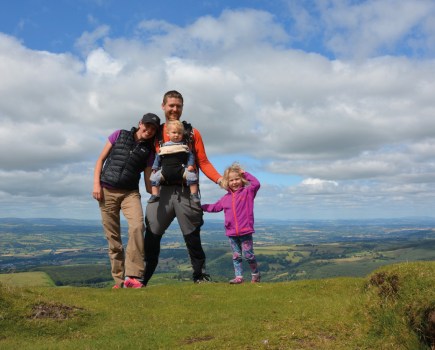 Family of four standing on high ground with panoramic countryside views behind