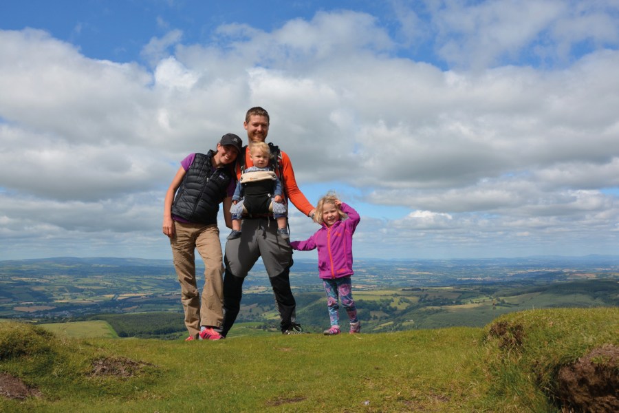 Family of four standing on high ground with panoramic countryside views behind