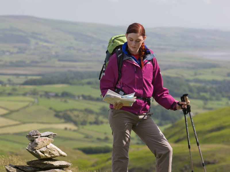 Woman reading a map ontop of a hill