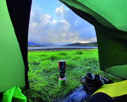 looking out on a field with a lake in the distance from the inside of a tent