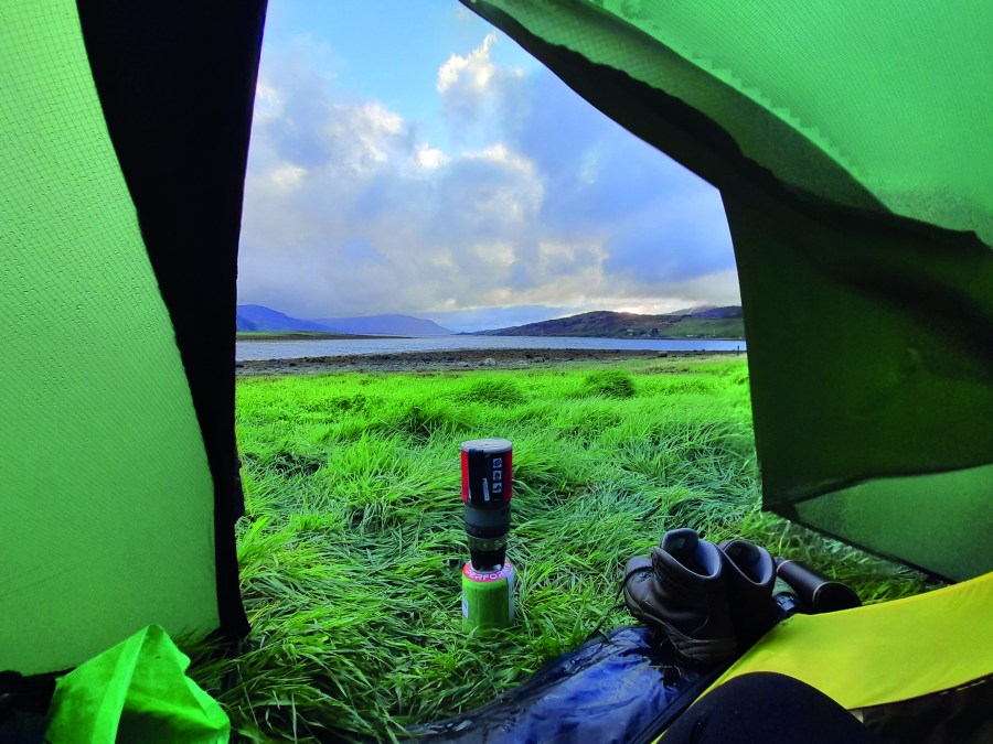 looking out on a field with a lake in the distance from the inside of a tent