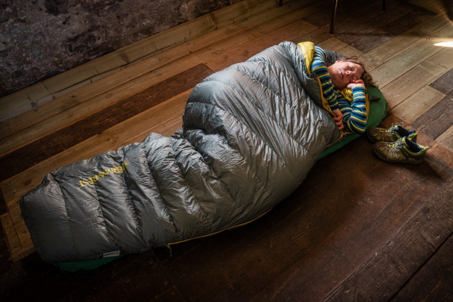 A hiker resting in a bothy wrapped in an insulating bag instead of one of the alternates to sleeping bags_credit David Lintern