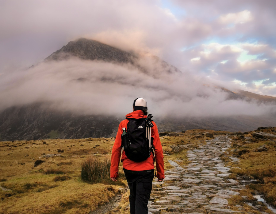 A walker looks into the cloud over Snowdonia's Ogwen Valley wearing a regular backpack for hiking