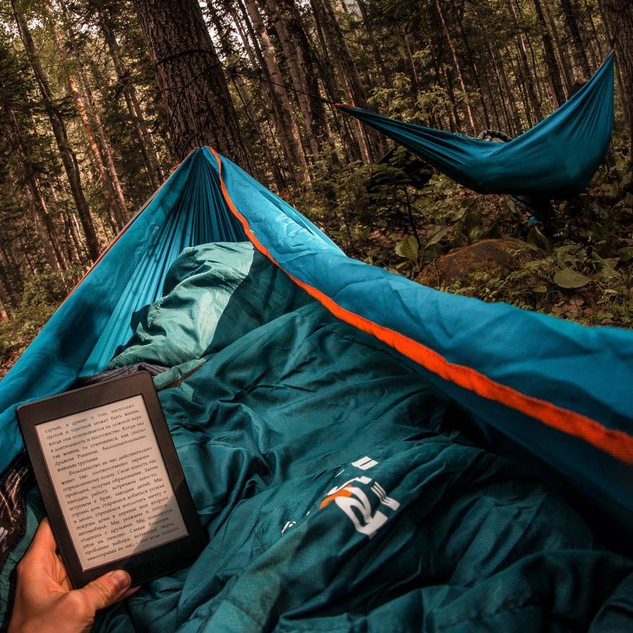 Hiker reading in hammock in woodland