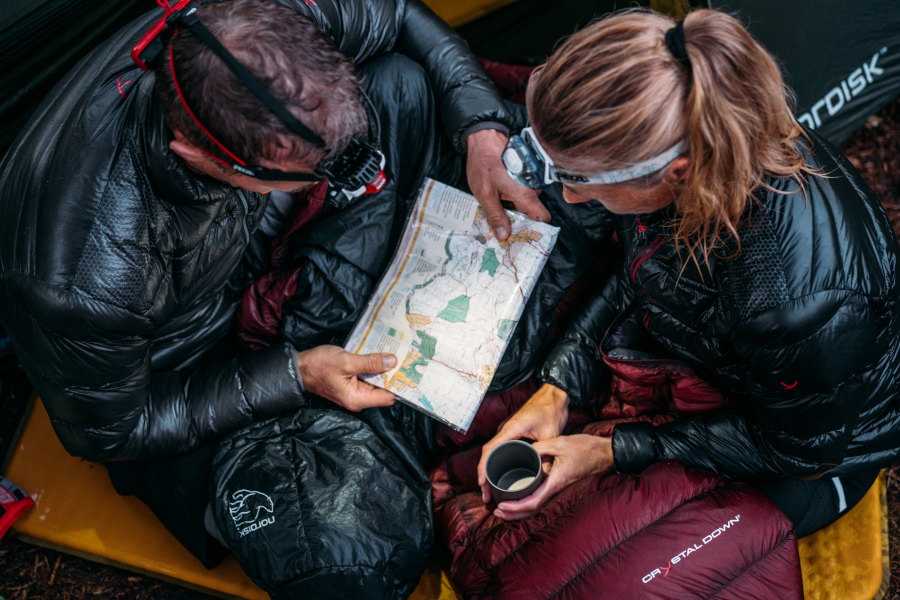 Couple sitting in sleeping bag reading map