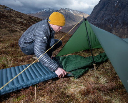 Man sliding sleeping mat into tent