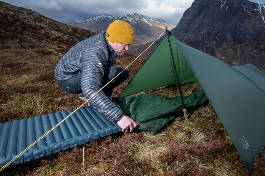 Man sliding sleeping mat into tent