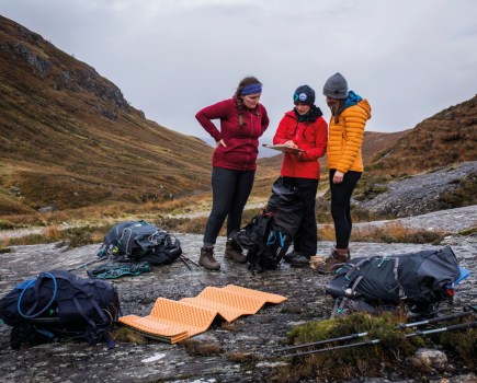 A group of women at their campsite looking at a map planning a route