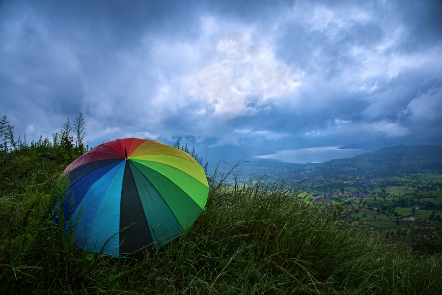 A gloomy day on a hill storm cloud approaching rainbow umbrella in forground