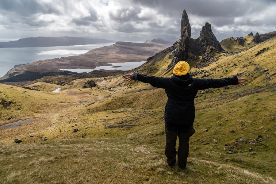 Woman standing looking at the Old Man of Storr in the Scottish Highlands