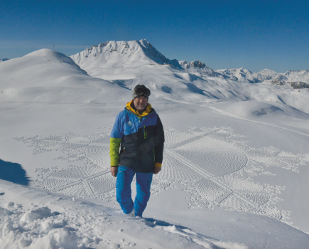 Simon Beck standing above his snow art at Marlou