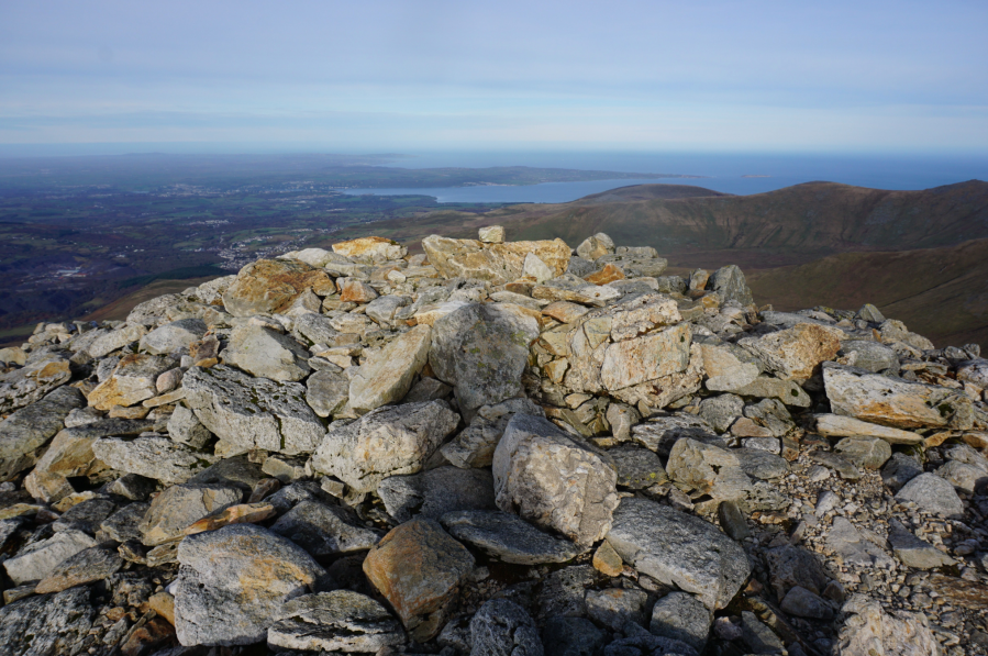 The summit cairn of Carnedd Llewelyn looking towards Anglesey.