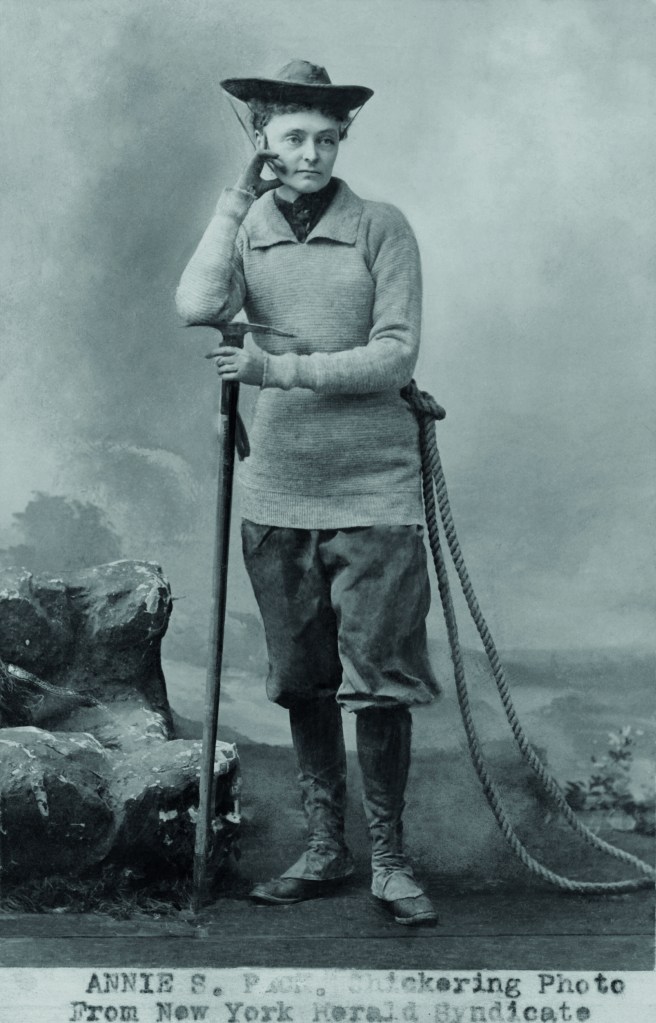 2BAC74C Miss Annie S. Peck, in her mountaineering gear, 1911. She wears a tunic sweater over trousers tucked into gaiters over climbing boots. In 1895, her masculine climbing costume was scandalous. In 1908, at the age of 58, she climbed Peru's Mount, reaching the height of 21,812, higher than and man or women had climbed to that date. Her claim was contested by Fanny & William Hunter Workman (BSLOC_2018_4_204)