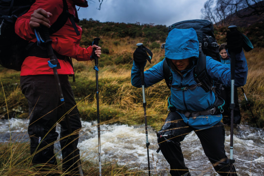 Iona Andean on a river crossing putting the best material for hiking trousers to the test