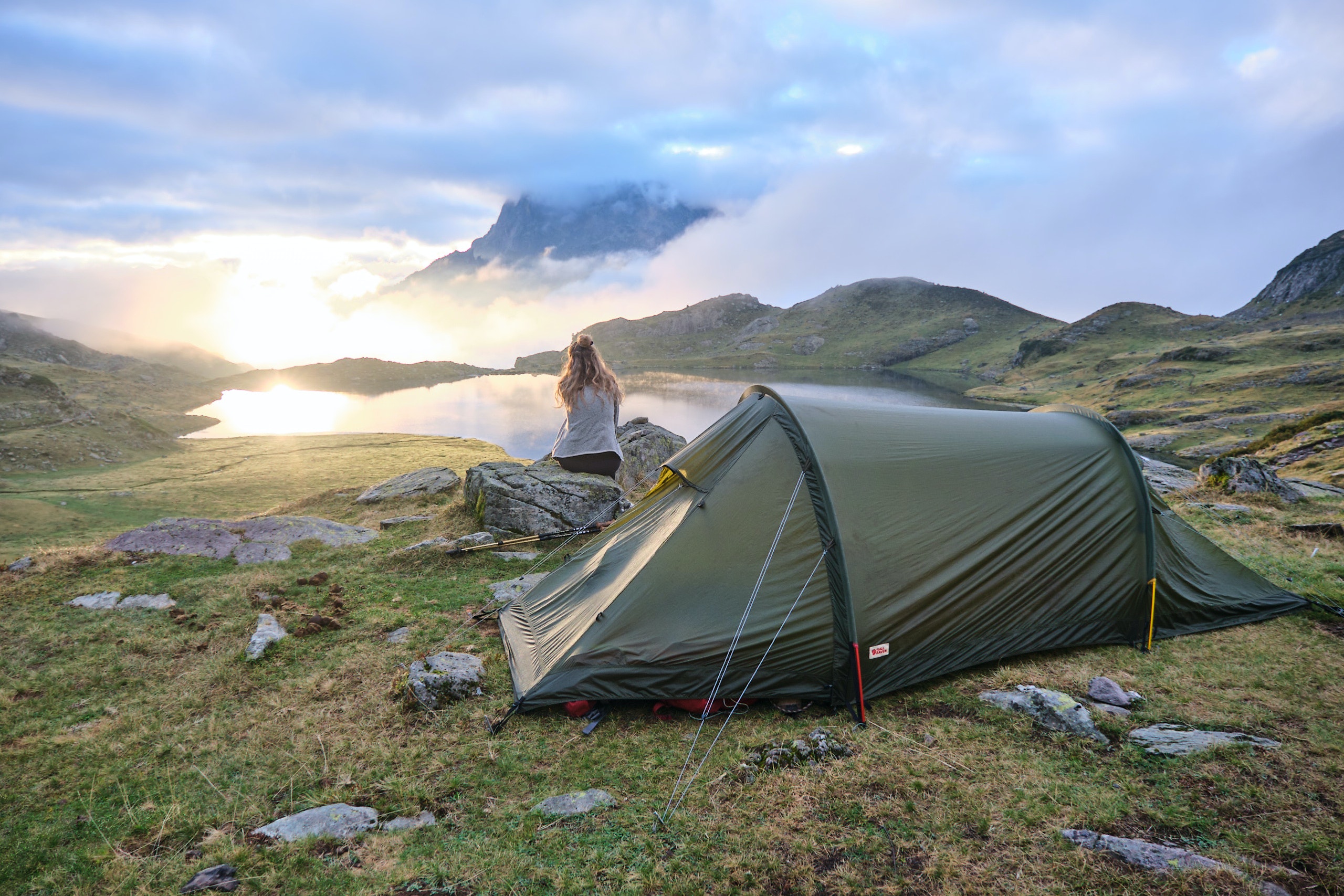 woman sitting on a rock beside her tent