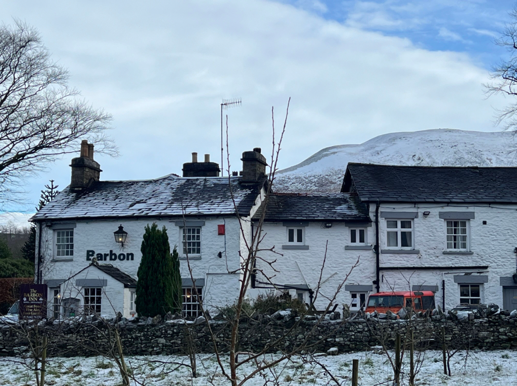 Middleton Fell rises behind the warm pub