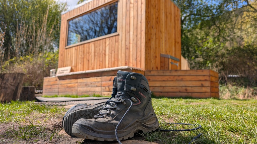 Hiking boots on the ground with WildEmber Bothy in the background. Credit: Julia Clarke