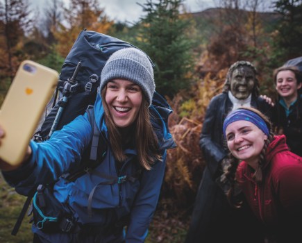 Four women all in Berghaus jackets smiling for a slefie with yellow smartphone