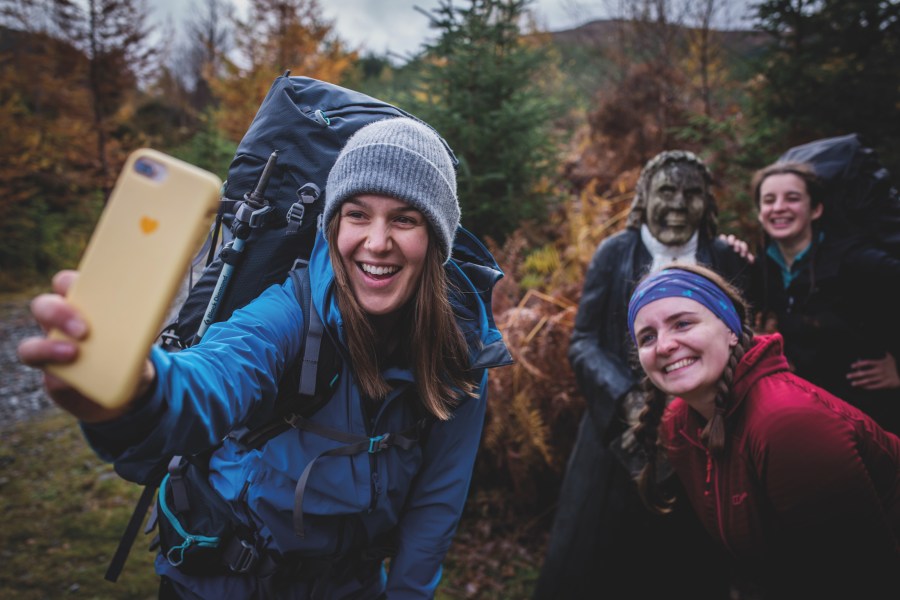 Four women all in Berghaus jackets smiling for a slefie with yellow smartphone